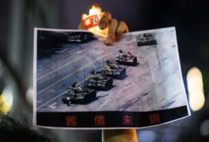 A man holds a poster of the famous 'Tank Man' standing in front of Chinese military tanks at Tiananmen Square in Beijing on June 5, 1989, during a candlelit remembrance in Victoria Park in Hong Kong on June 4, 2020.